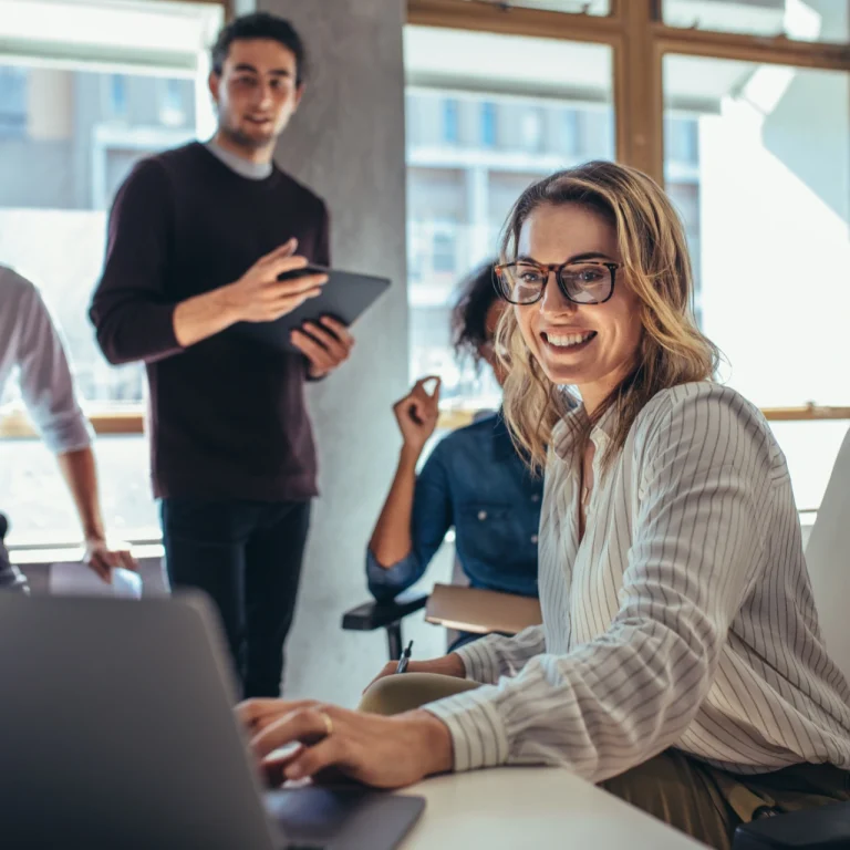 Digital marketing agency team collaborating in an office while reviewing work on a laptop during a strategy meeting.