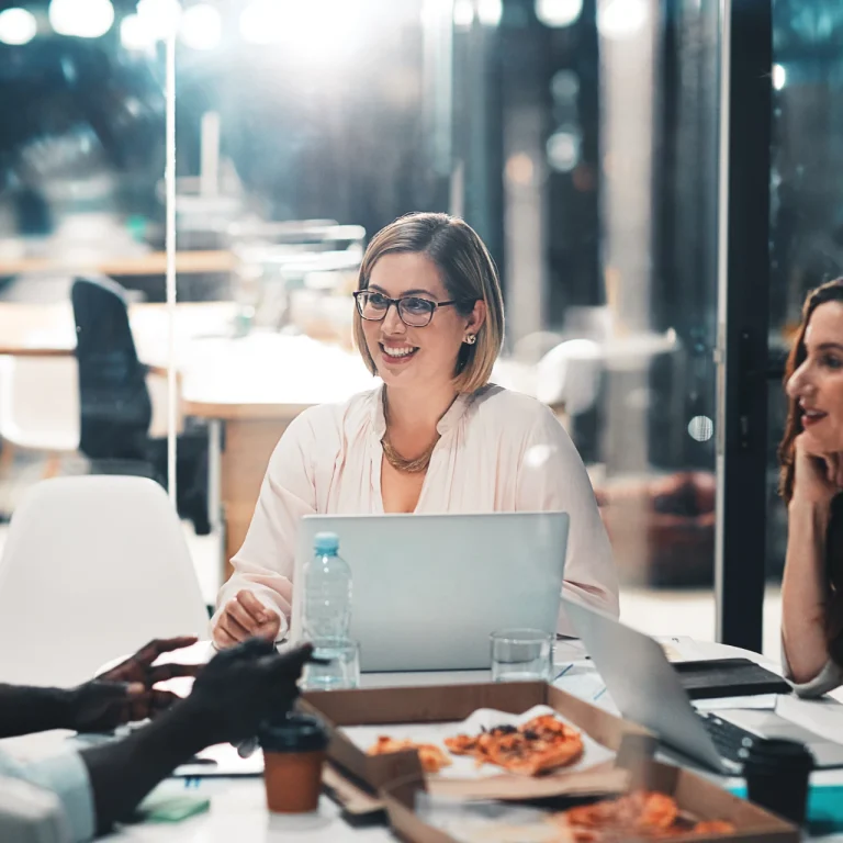 Team members at a digital marketing agency discussing strategy during a late-night office meeting with laptops and documents.