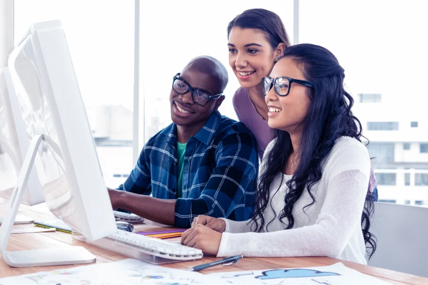Virtual assistant support team collaborating at a desktop computer in a modern office