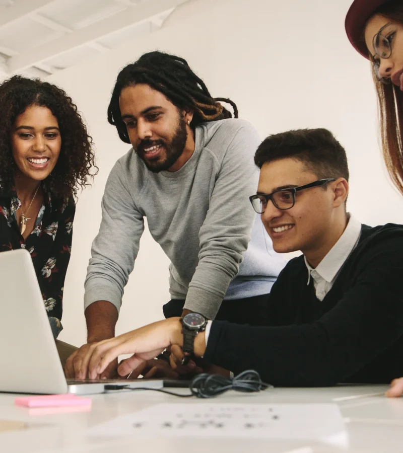 AI solution built to solve real business workflows with a diverse team collaborating around a laptop in an office