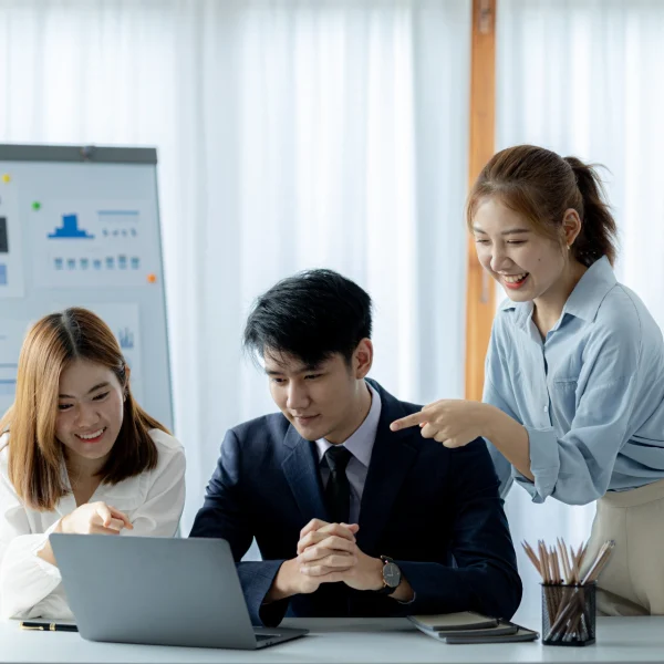 Startup team reviewing data on a laptop and discussing ideas together in a bright office workspace.